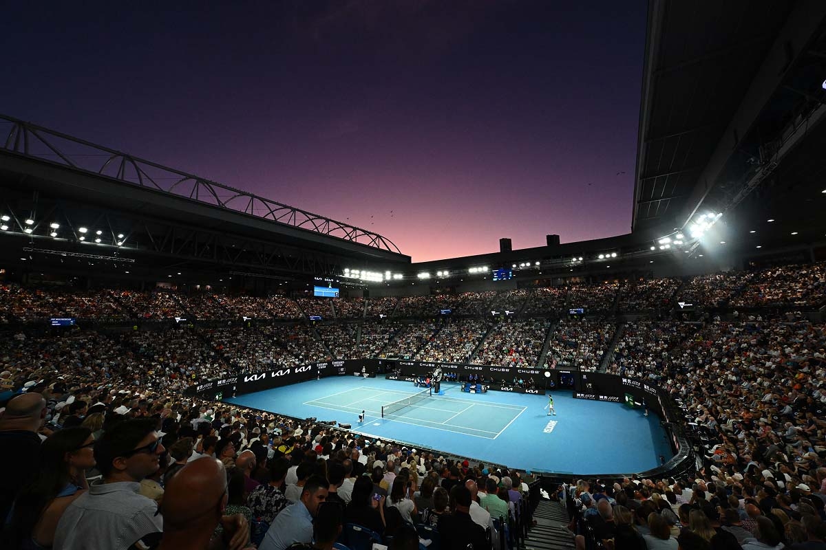 A tennis player, possibly James Duckworth or Jannik Sinner, serving during a match at an outdoor stadium.